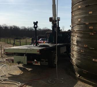 A large truck parked next to a tall grain bin.