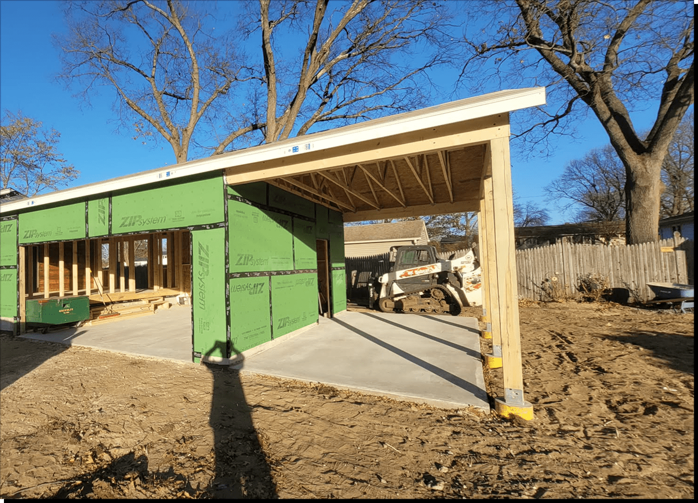 Partially constructed garage with green sheathing.