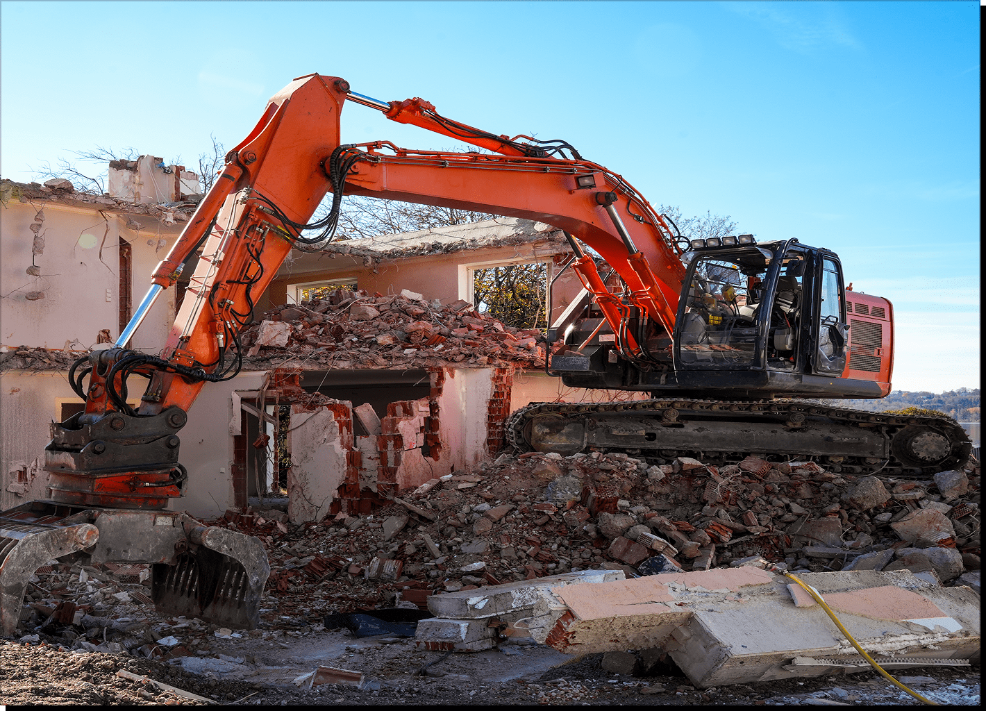Excavator demolishing a building under clear sky.