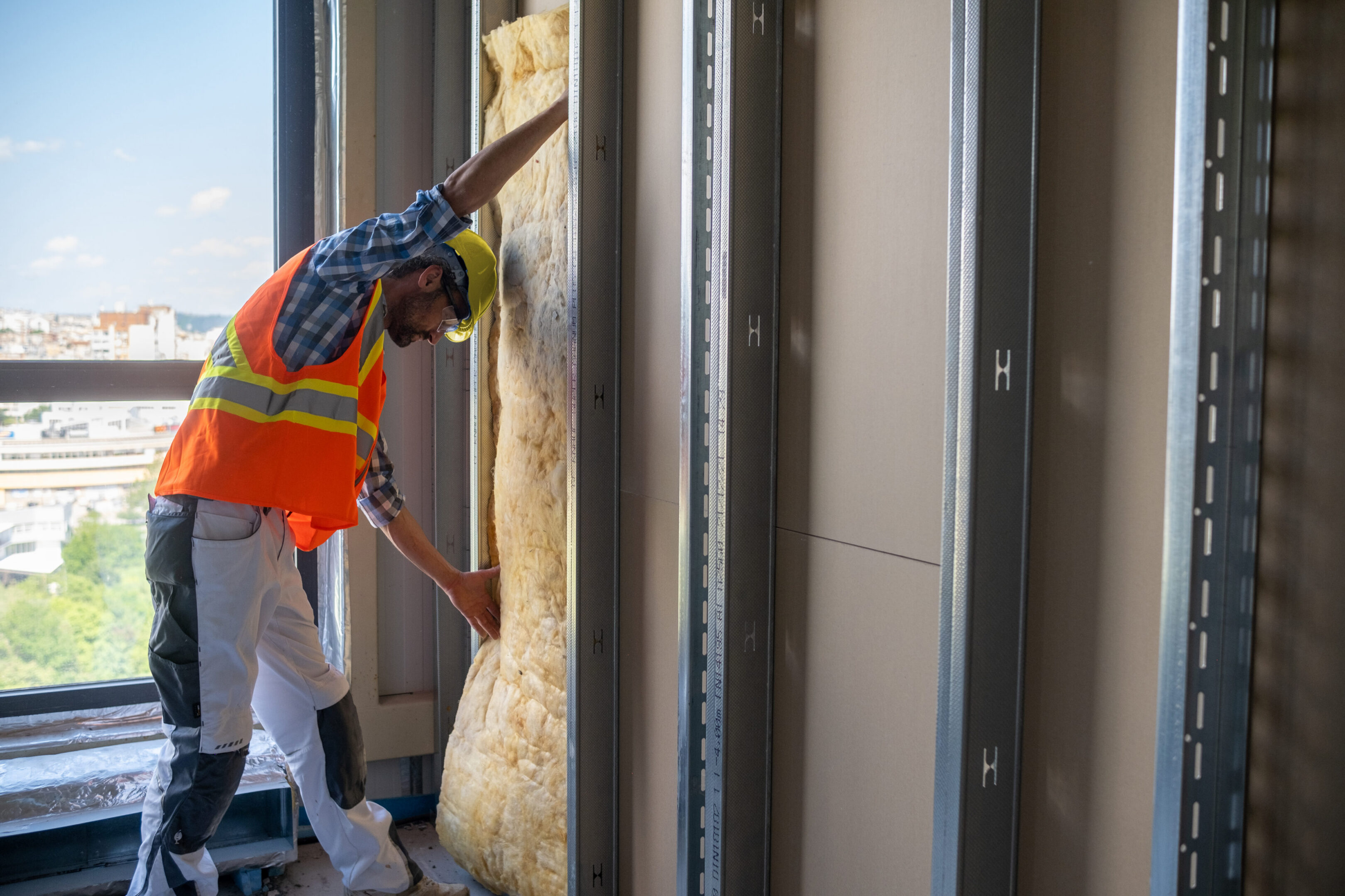 Worker installing insulation by window frame.