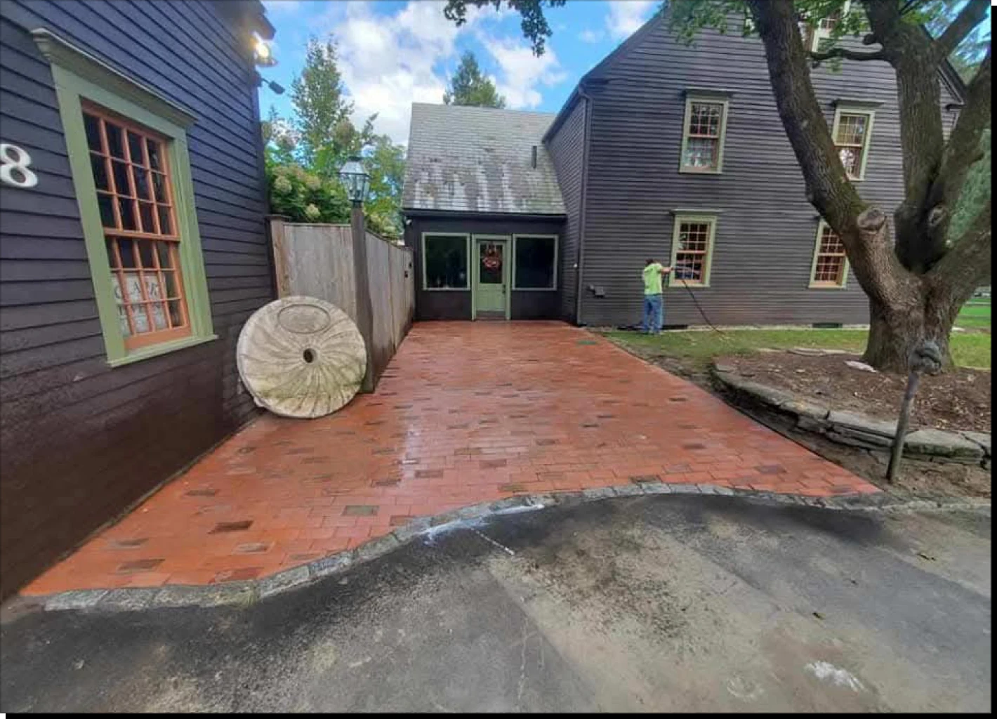 Brick patio between two historic wooden buildings.