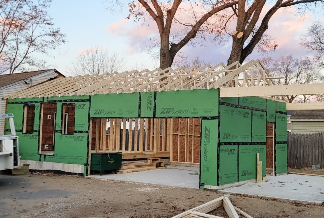 House under construction with green sheathing panels.