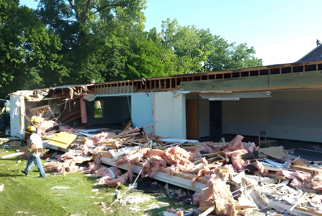 House partially collapsed with debris and trees.